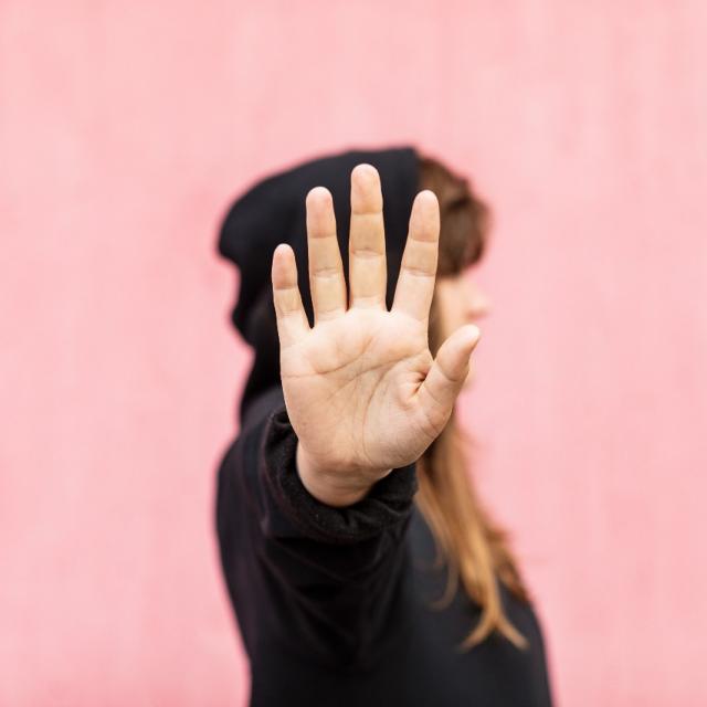 Bild på en kvinna som har handen uppsträckt framför sig som ett stop-tecken